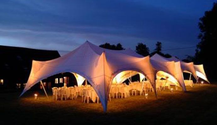 Evening marquee with warm interior lighting and round dining tables
